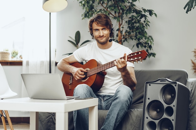 Young man watching guitar tutorial on his laptop