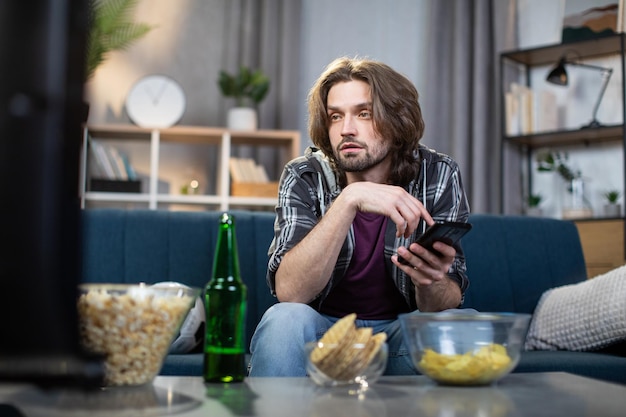 Young man watching sport program on TV