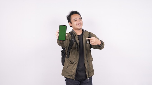 The young man wearing a bag isolated on a white space pointed greenscreen phone