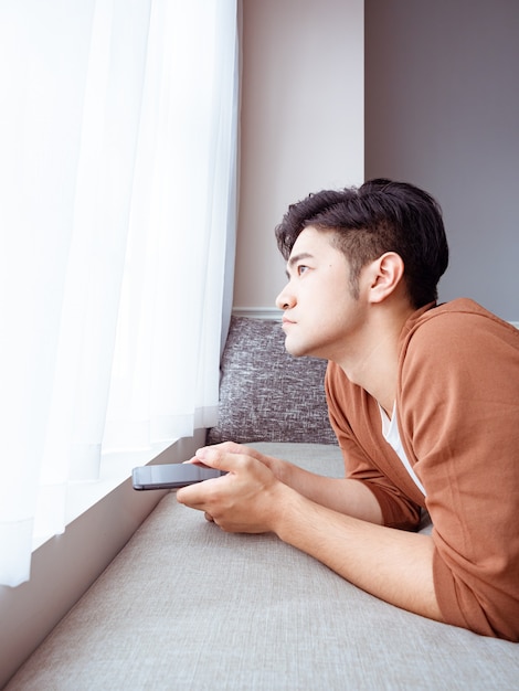 Young man wearing casual clothes and using smartphone at home