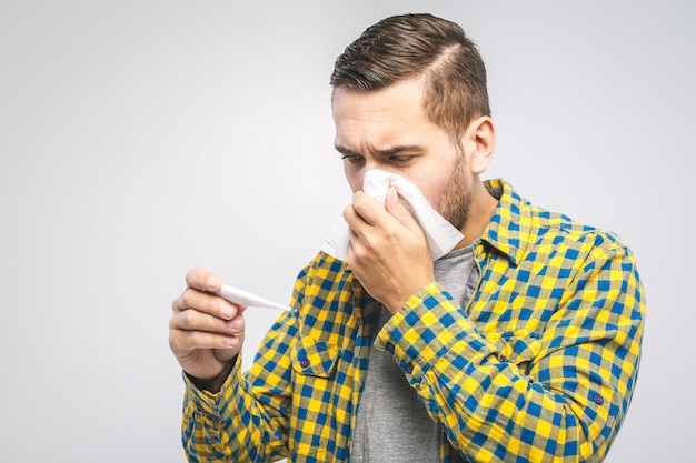 Young man wearing a casual shirt blowing his nose