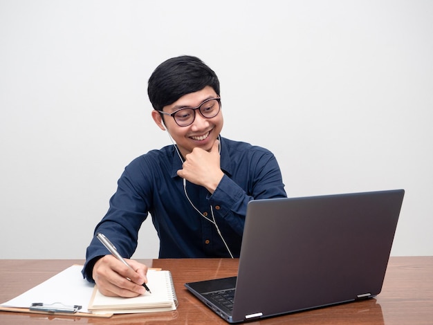 Young man wearing earphone working with laptop on tableMan working at workplace