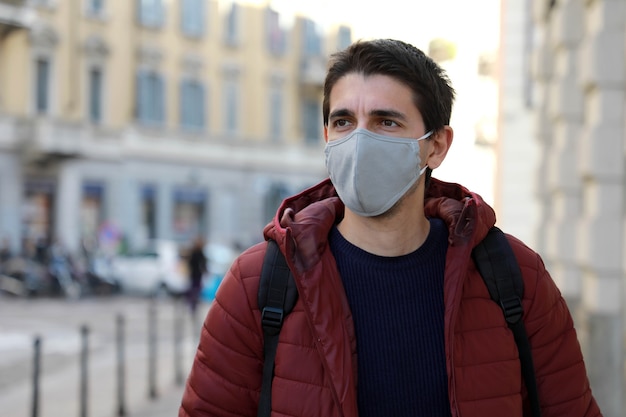 Young man wearing face mask walking down the street looking to the side