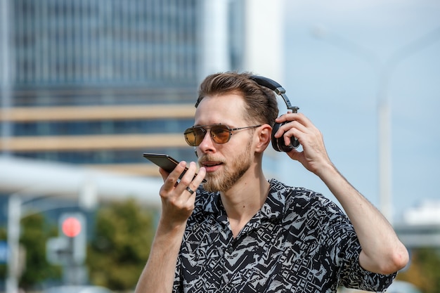 A young man wearing headphones and sunglasses listens to music