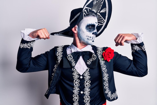 Photo young man wearing mexican day of the dead costume over white showing arms muscles smiling proud fitness concept