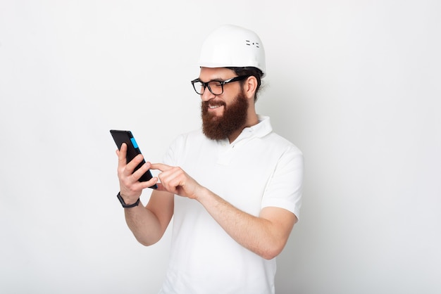 Young man wearing a protection hard hat is looking at his tablet.