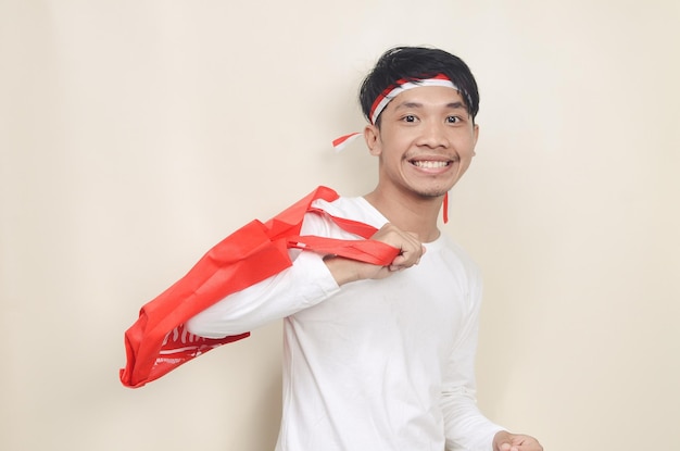 Young man wearing ribbon on his head holding shopping bags on isolated background Independence day discount concept