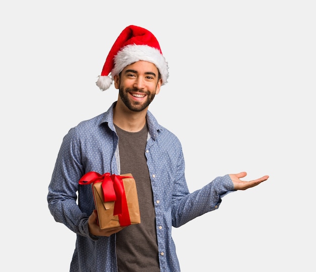 Young man wearing santa hat holding something with hands