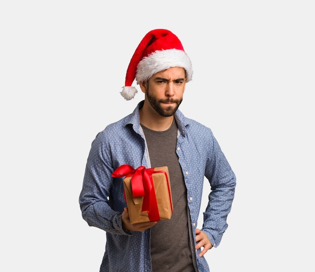 Young man wearing santa hat scolding someone very angry