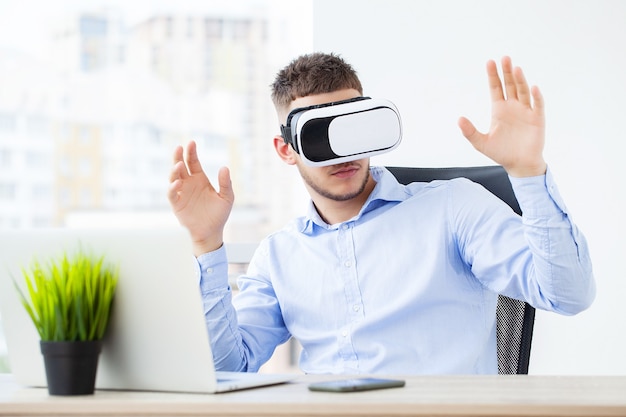 Young man wearing virtual reality glasses in modern office.