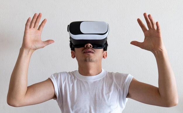 Photo young man wearing virtual reality goggles headset on gray background concept of vr video game future gadgets and technology