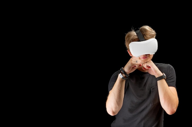 Young man wearing virtual reality VR glasses goggles isolated on black background Inside A Metaverse