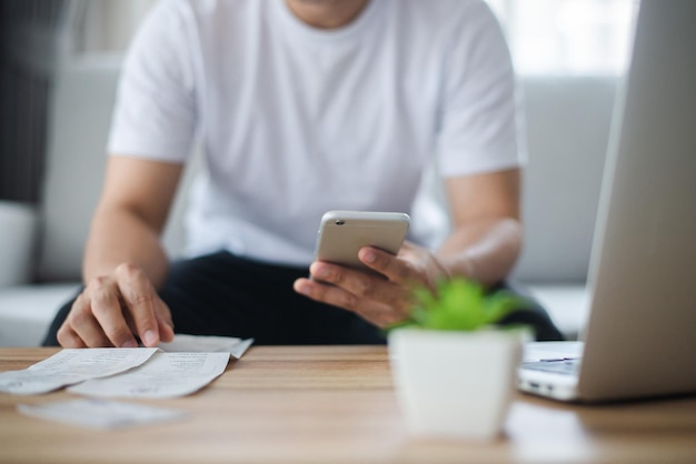 Young man wearing wear casual clothes hand holding and using smart phone paying bills.