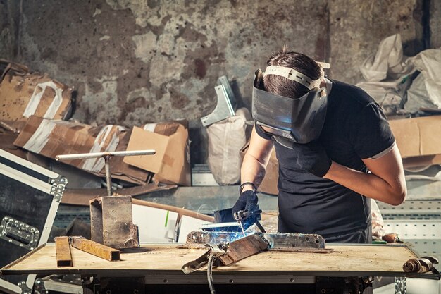 A young man welder   welding a metal with arc welding machine  in the workshop