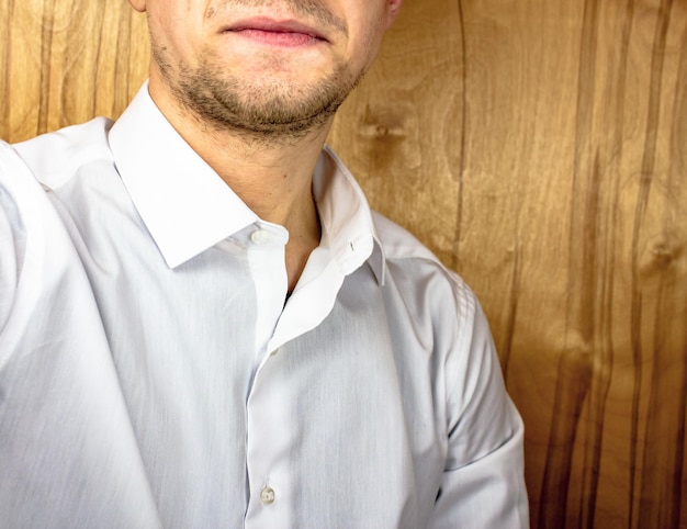 Young man in a white shirt smilingA young man in a classic white shirt an office worker a businessman takes a selfie with one hand behind the scenes