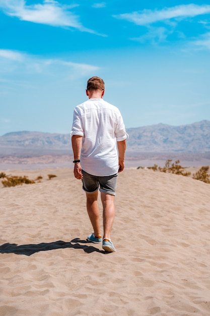 A young man in a white shirt walks through the picturesque desert in Death Valley