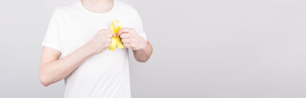 Young man in white t-shirt holding yellow ribbon awareness symbol for suicide