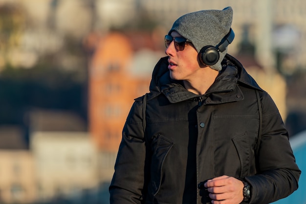 Young Man in the Winter City Streets with Headphones