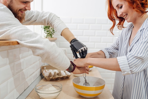 Young man with artificial limb are cooking on kitchen with his girlfriend