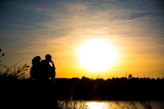 Young man with a backpack enjoying the sunset on top of the mountain Tourist traveler