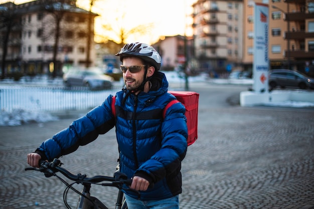 Young man with a backpack for food delivery and a bicycle protection helmet. Home work, bike ride, pizza delivery