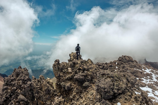 Young man with backpack standing on top of mountain