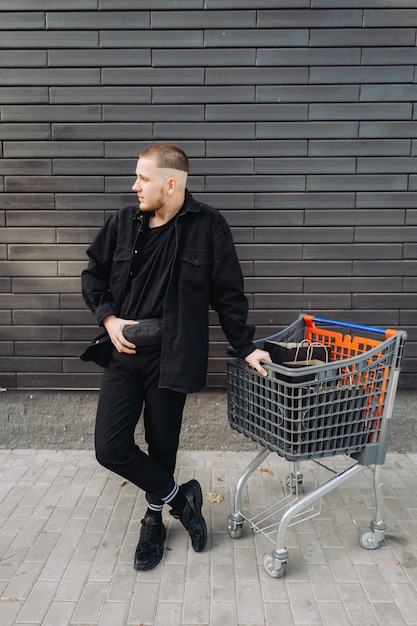 Young man with bags and trolley on Black Friday