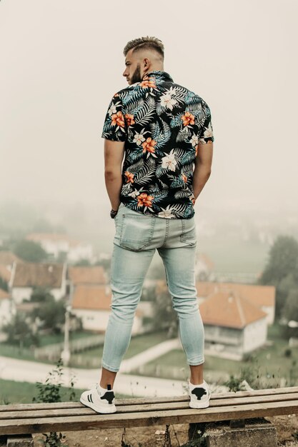 Young man with beard and flowered shirt posing in nature