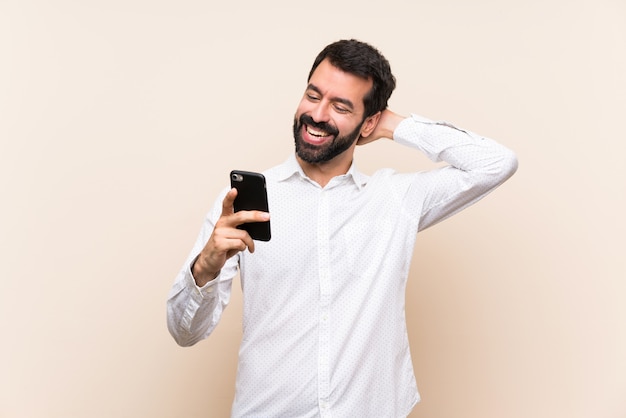 Young man with beard holding a mobile smiling