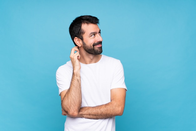 Young man with beard  over isolated blue wall thinking an idea