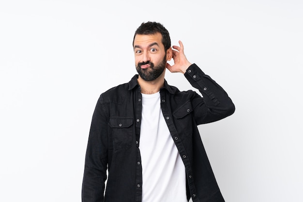 Young man with beard over isolated white wall having doubts