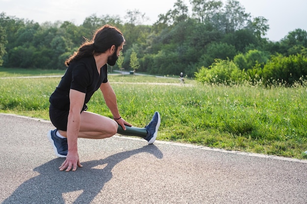 Young man with beard and prosthetic leg stretching to warm up