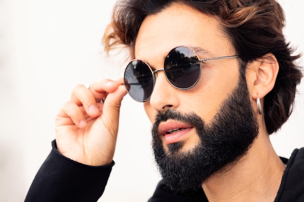 Young man with beard putting on sunglasses