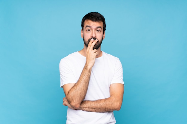 Young man with beard surprised and shocked while looking right