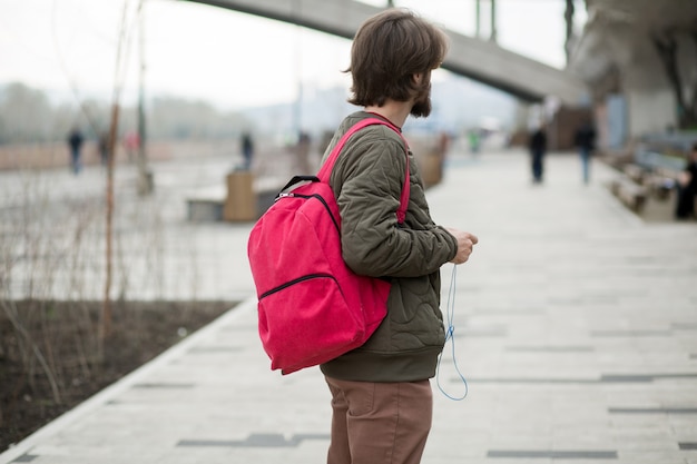 Young man with a beard with a backpack and headphones on the street