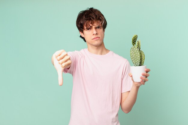 Young man with a cactus feeling cross,showing thumbs down