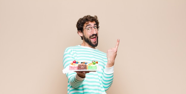 Photo young man with a cake against flat wall