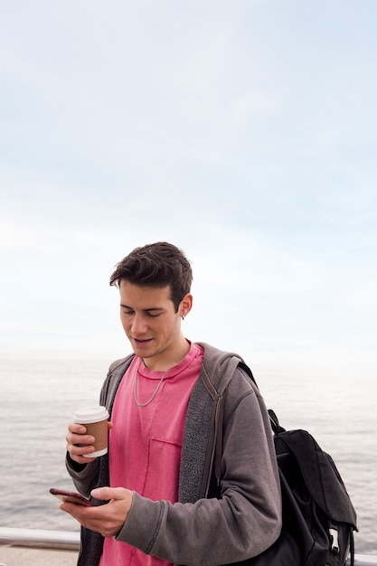 Young man with a coffee using a mobile phone