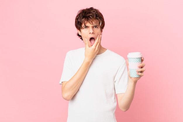 Young man with a coffee with mouth and eyes wide open and hand on chin