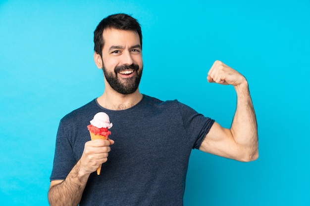 Young man with a cornet ice cream over isolated blue wall doing strong gesture