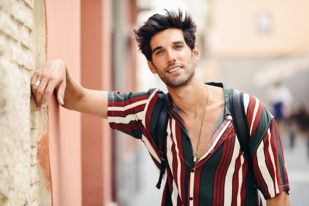 young man with dark hair and modern hairstyle wearing casual clothes outdoors