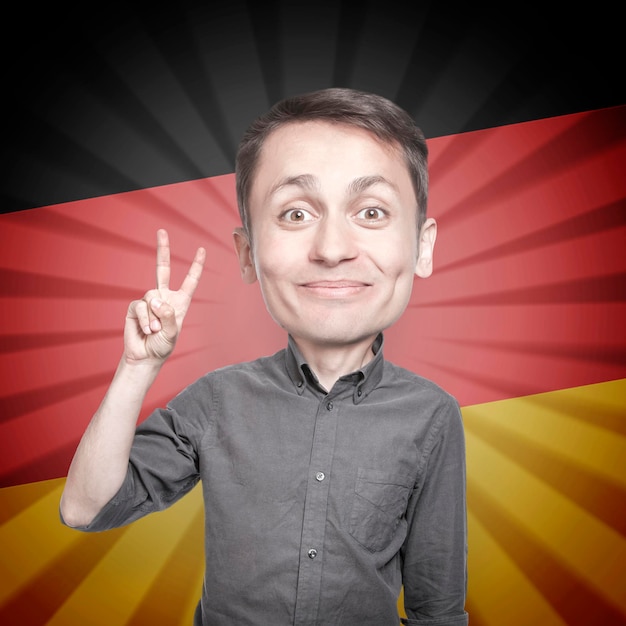 Young man with the fingers in a victory sign on background of the flag of Germany