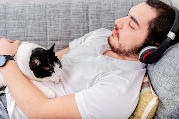 Young man with fluffy cat lying on a sofa