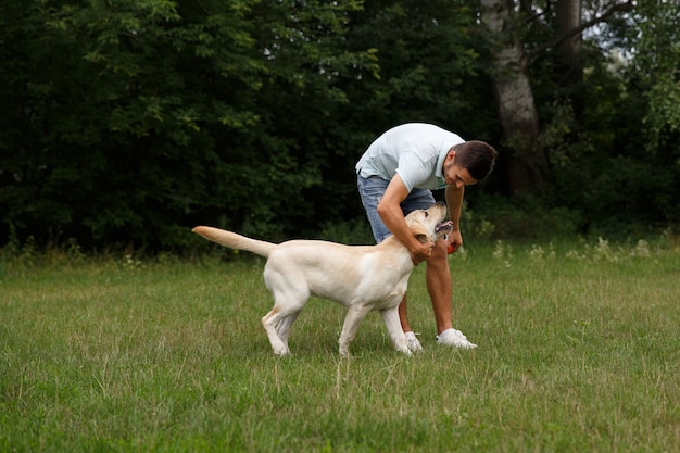 Young man with happy labrador in the park