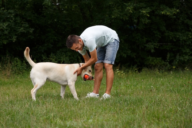 Young man with happy labrador in the park