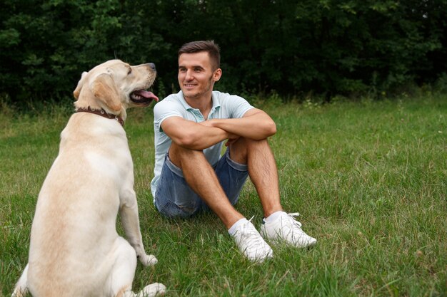 Young man with happy labrador in the park