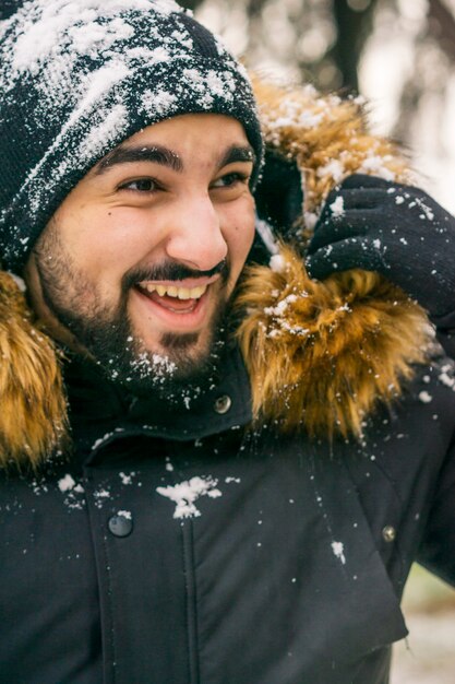 Young man with hat smiling in snow