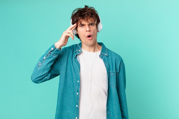 Young man with headphones looking surprised, realizing a new thought, idea or concept