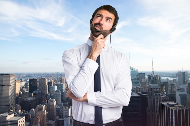 Young man with a headset thinking on unfocused background