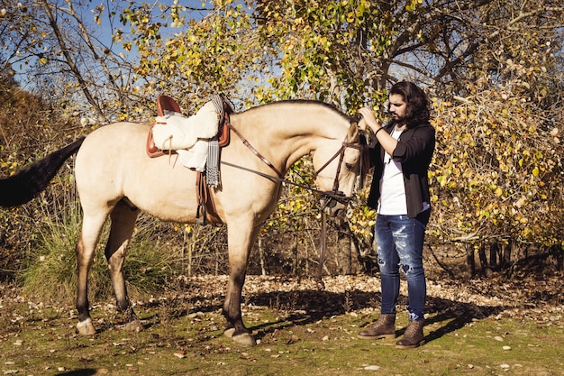 Young man with his horse walking through the field